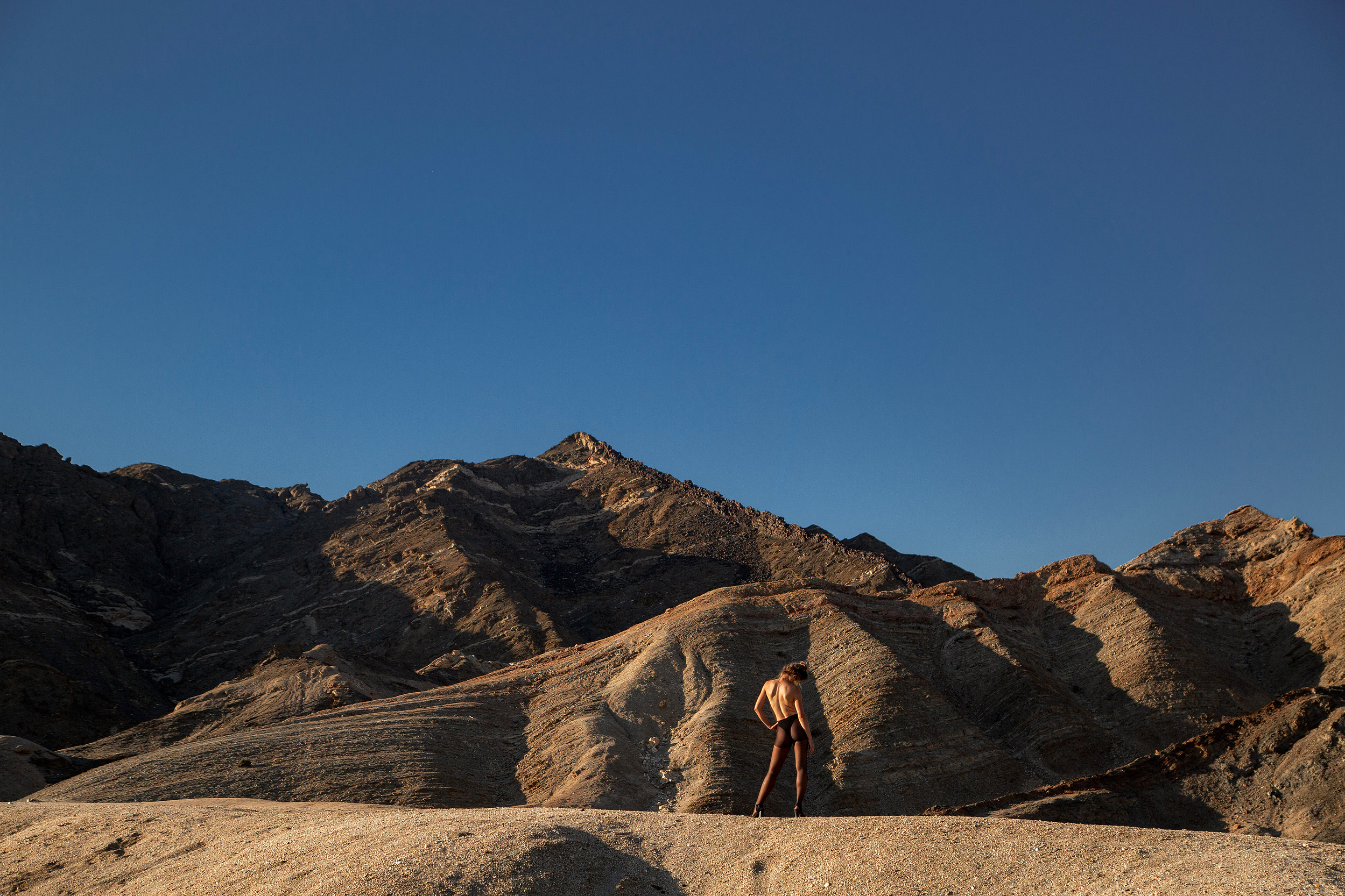 Geological mountain landscape, lone figure walking the lower frame, sunlit